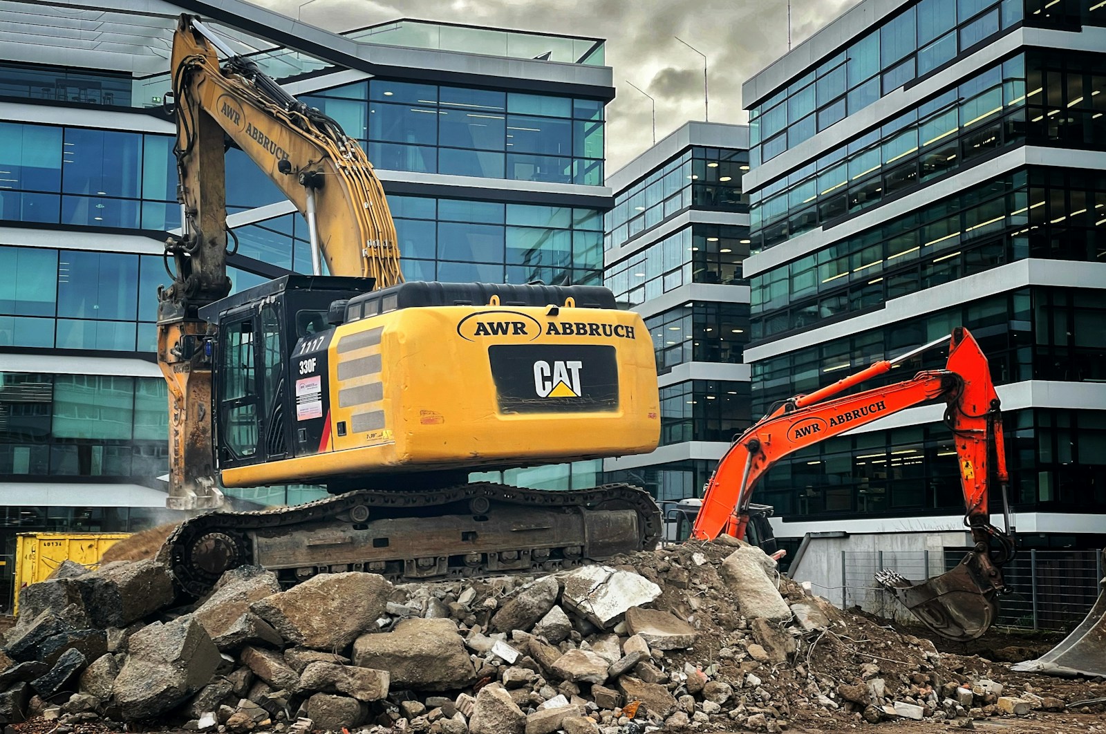 a bulldozer digging through a pile of rubble in front of a building