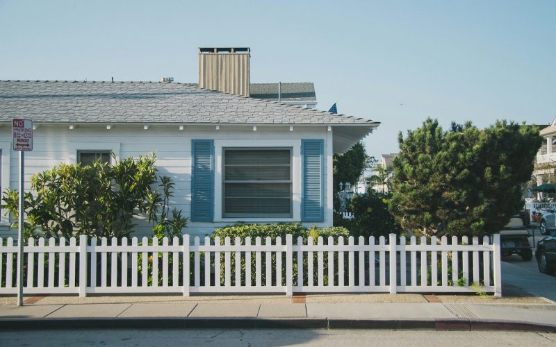 white and blue house beside fence